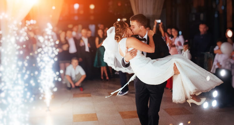 A bride and groom kiss in front of their guests at a wedding reception